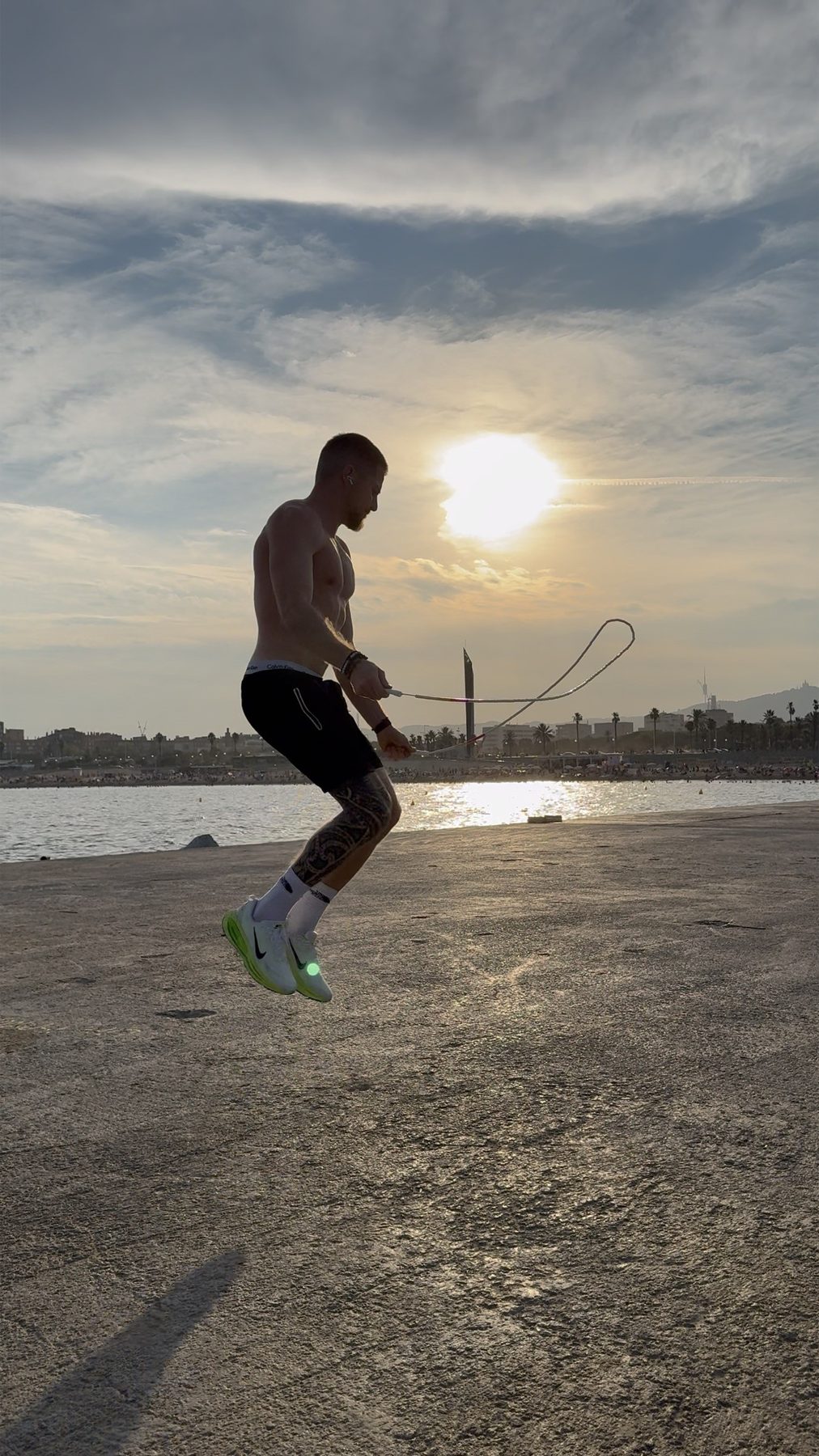 Kilian saute à la corde face au soleil couchant, en bord de mer